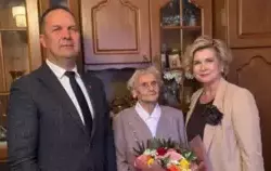 Na zdjęciu widzimy trzy osoby stojące w elegancko urządzonym, domowym wnętrzu, prawdopodobnie podczas uroczystości rodzinnej lub oficjalnej wizyty z okazji jubileuszu.